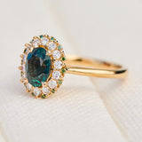 oval teal montana sapphire engagement ring in yellow gold with a diamond halo