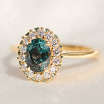 oval teal montana sapphire engagement ring in yellow gold with a diamond halo