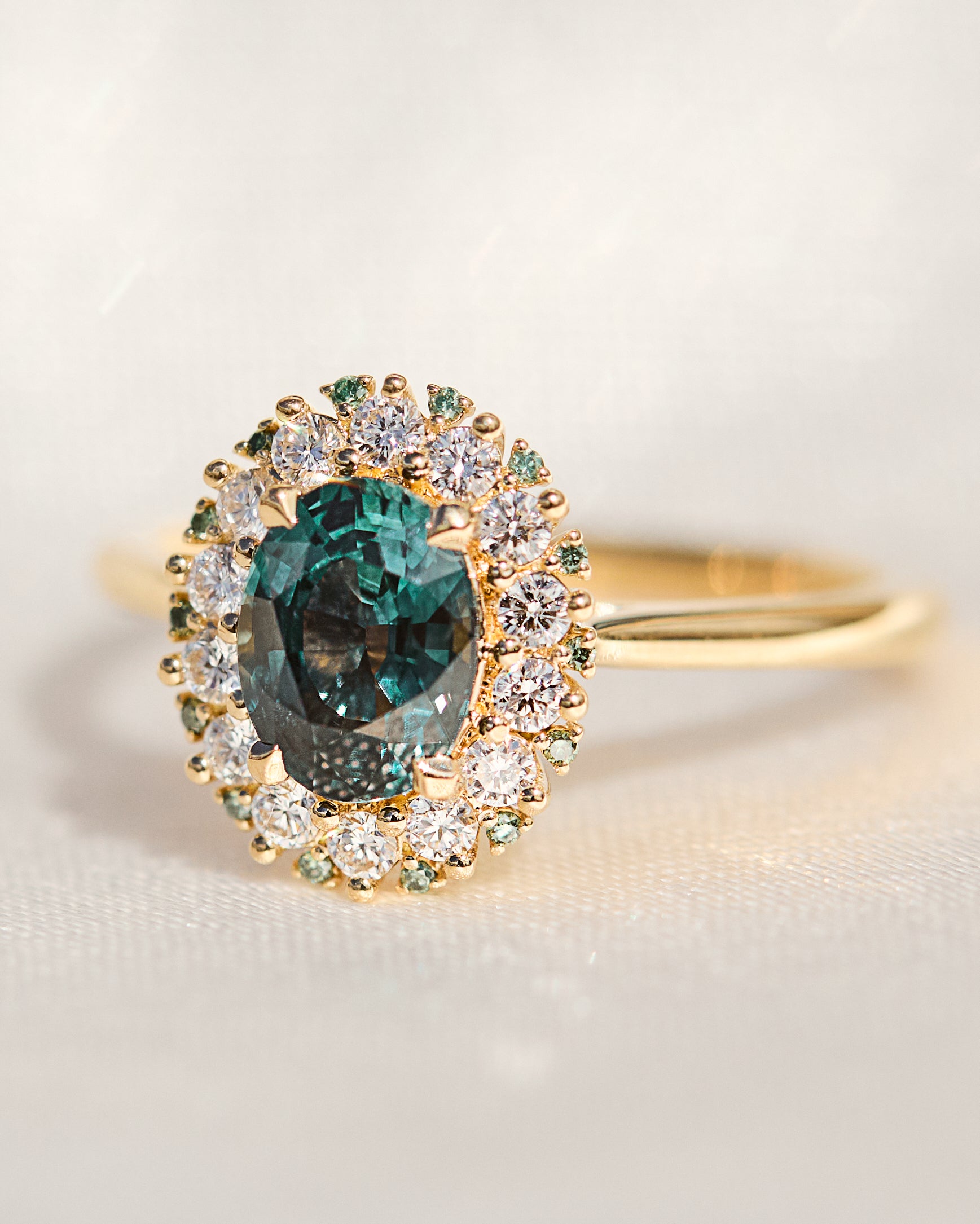 oval teal montana sapphire engagement ring in yellow gold with a diamond halo