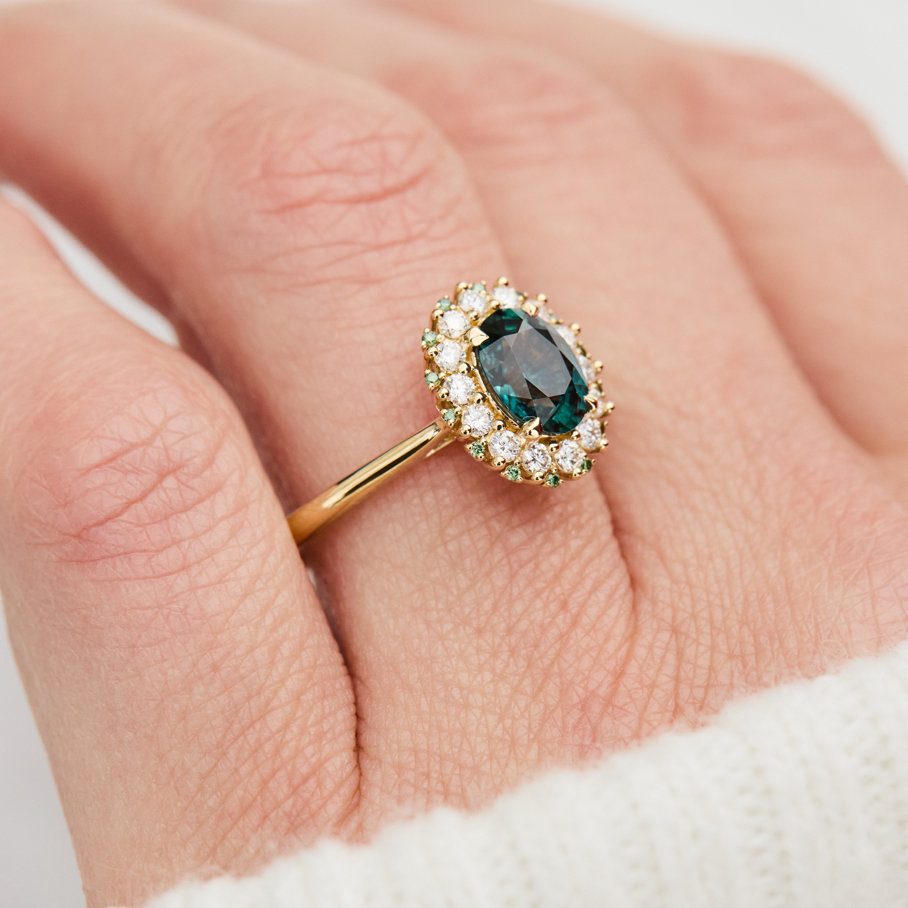 oval teal montana sapphire engagement ring in yellow gold with a diamond halo