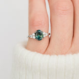 oval teal sapphire engagement ring set in platinum accented by six side diamonds