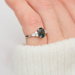 oval teal sapphire engagement ring set in platinum accented by six side diamonds