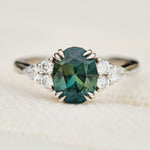 oval teal sapphire engagement ring set in platinum accented by six side diamonds