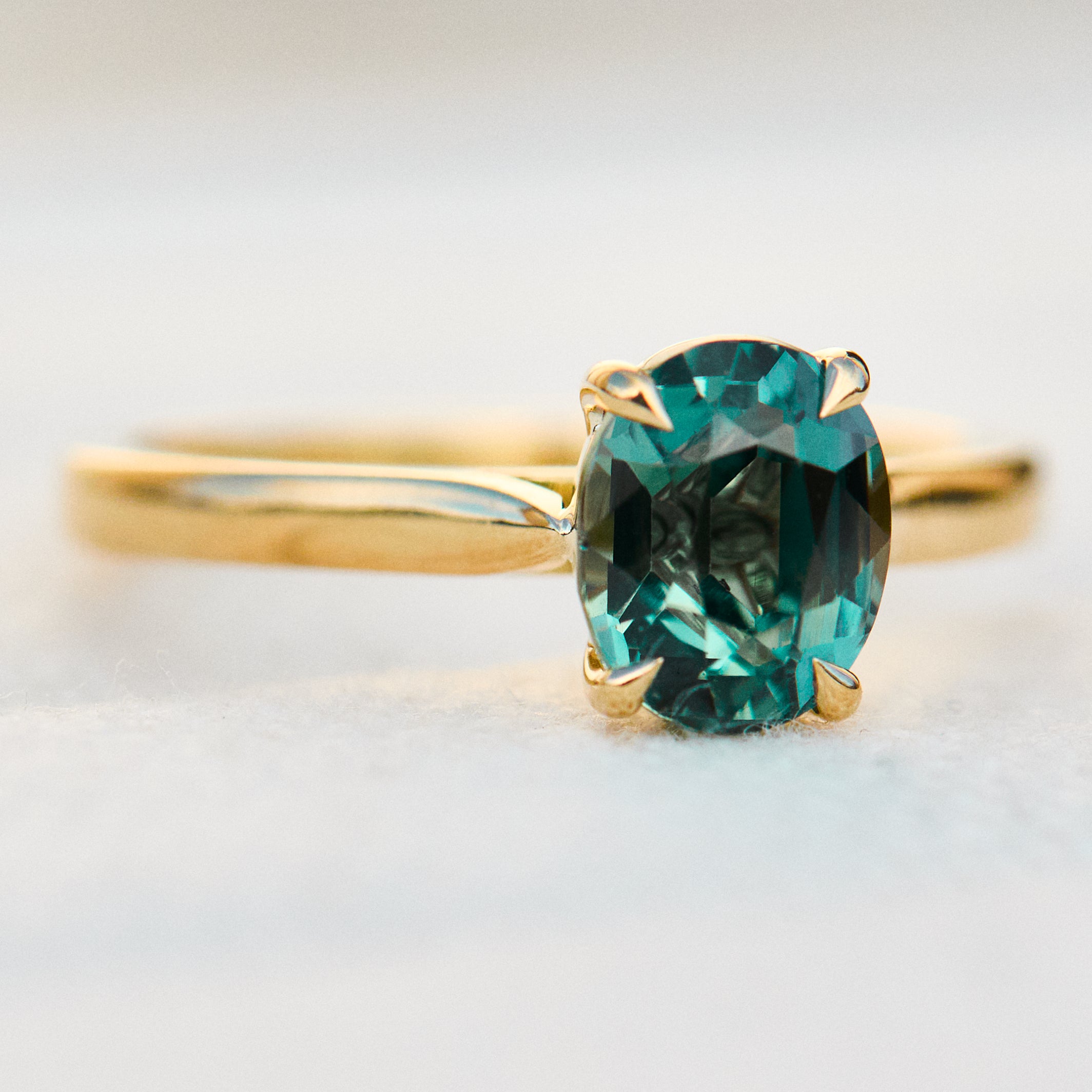 oval teal sapphire solitaire engagement ring in yellow gold