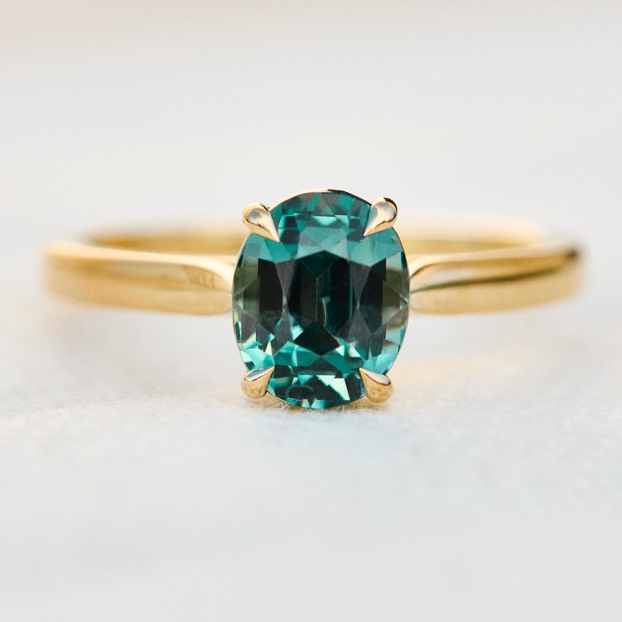 oval teal sapphire solitaire engagement ring in yellow gold