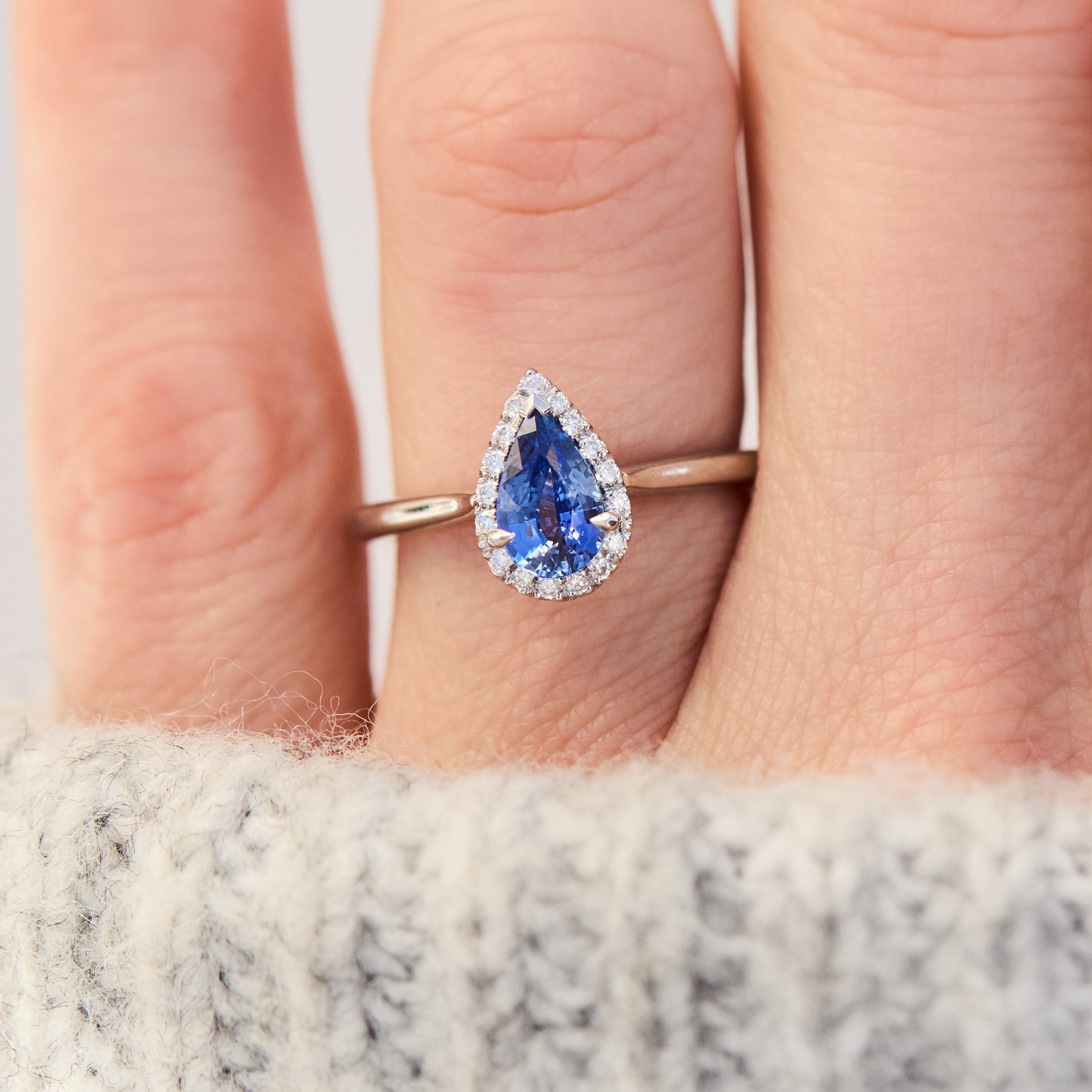 pear shape blue sapphire engagement ring with a pave halo of diamonds set in platinum