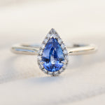 pear shape blue sapphire engagement ring with a pave diamond halo set in platinum