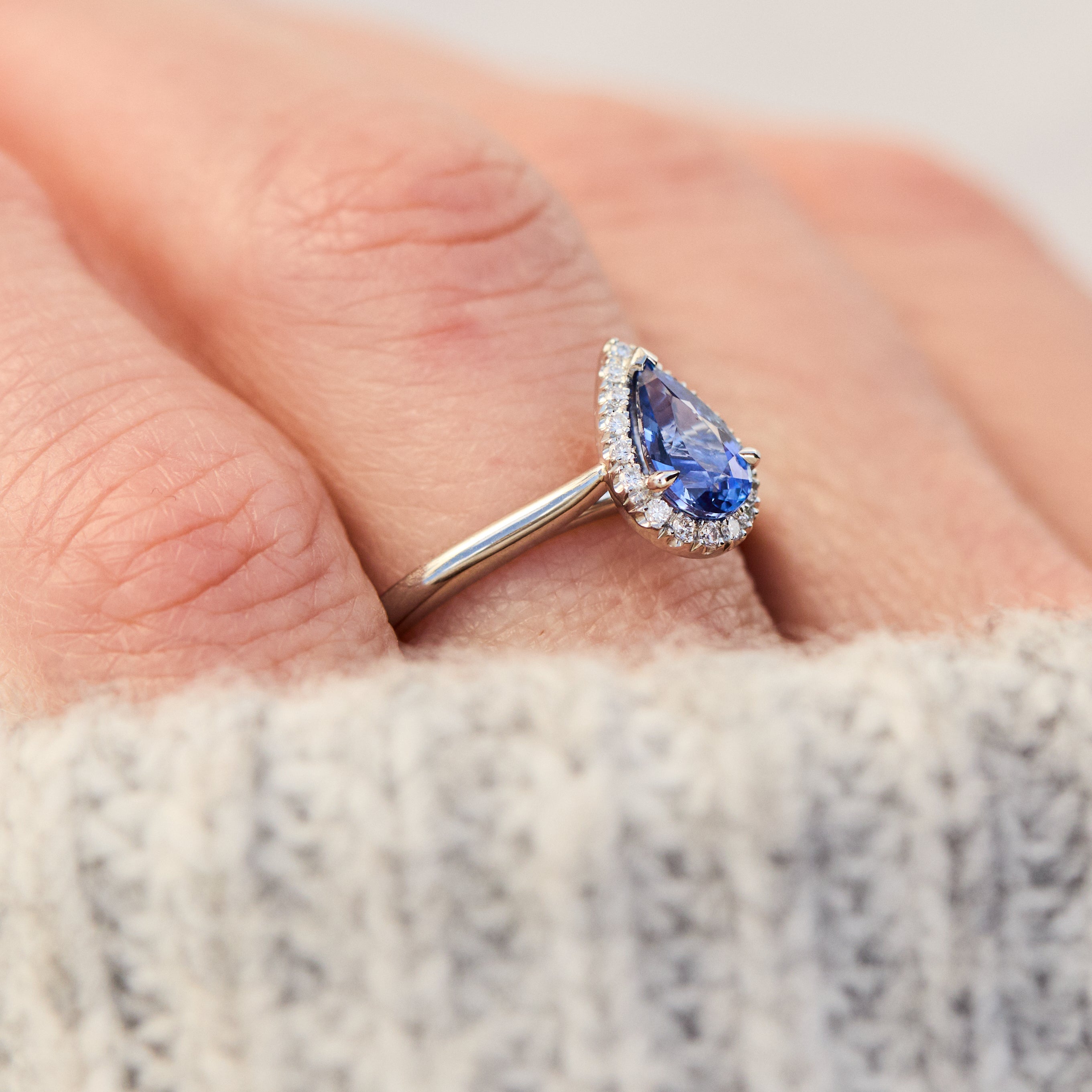 pear shape blue sapphire engagement ring with a pave diamond halo set in platinum
