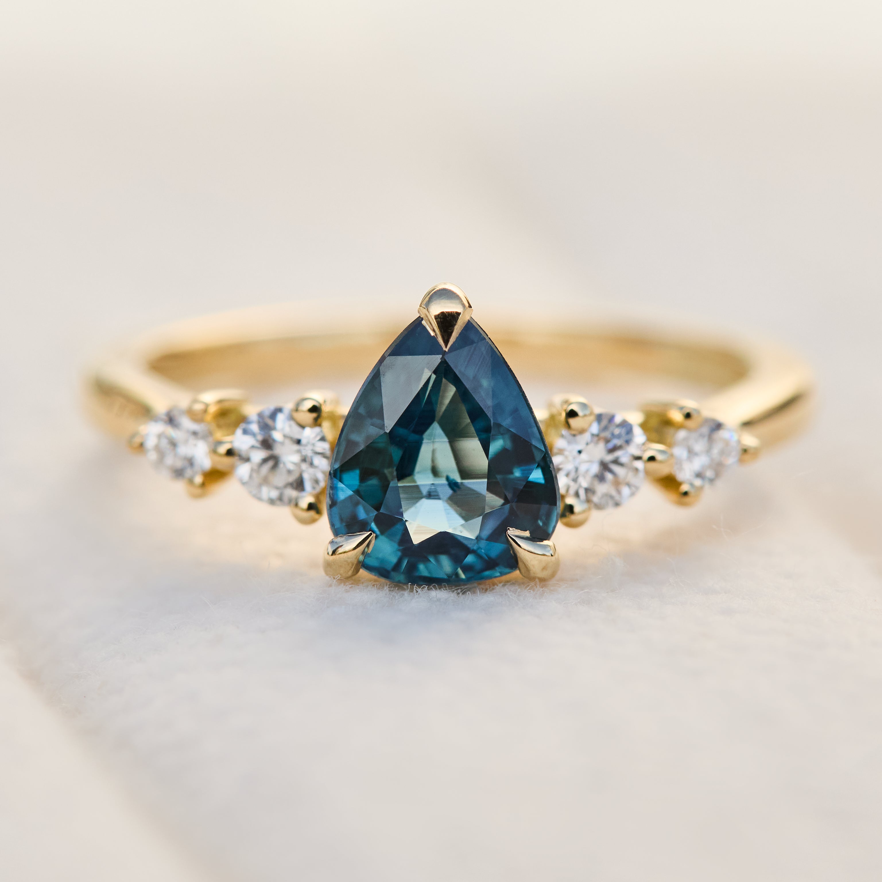 pear shape blue teal sapphire engagement ring set in yellow gold