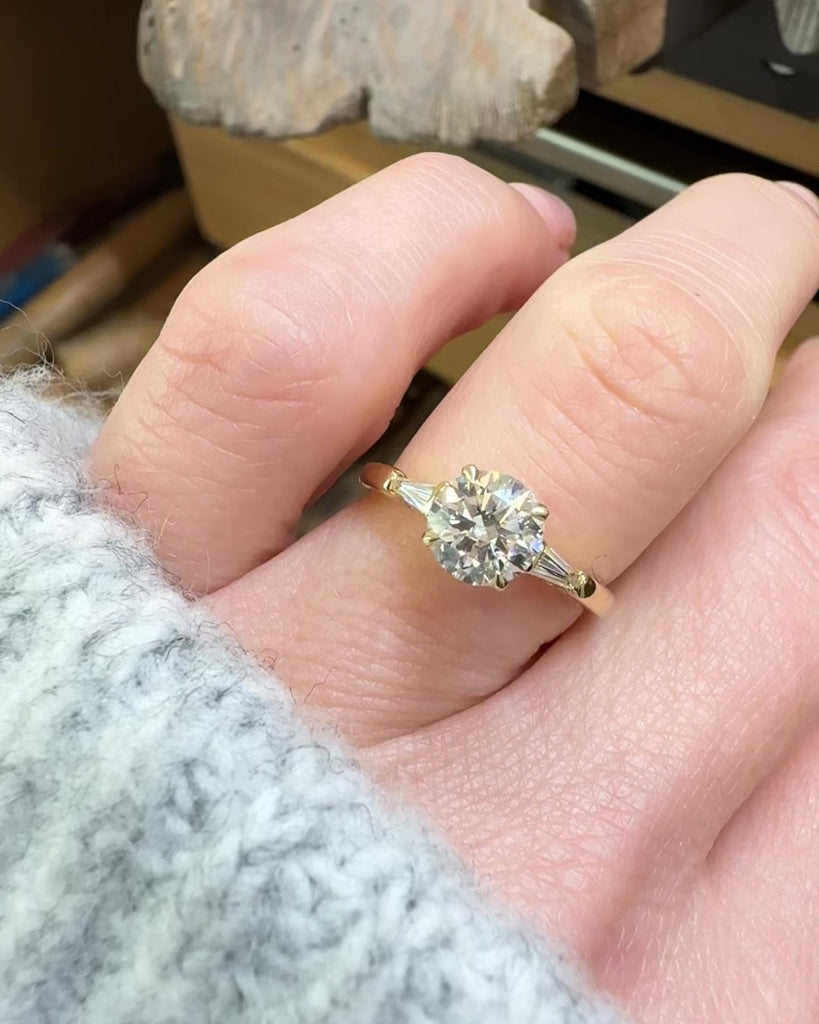 round brilliant cut diamond trilogy engagement ring with tapered baguette shoulders