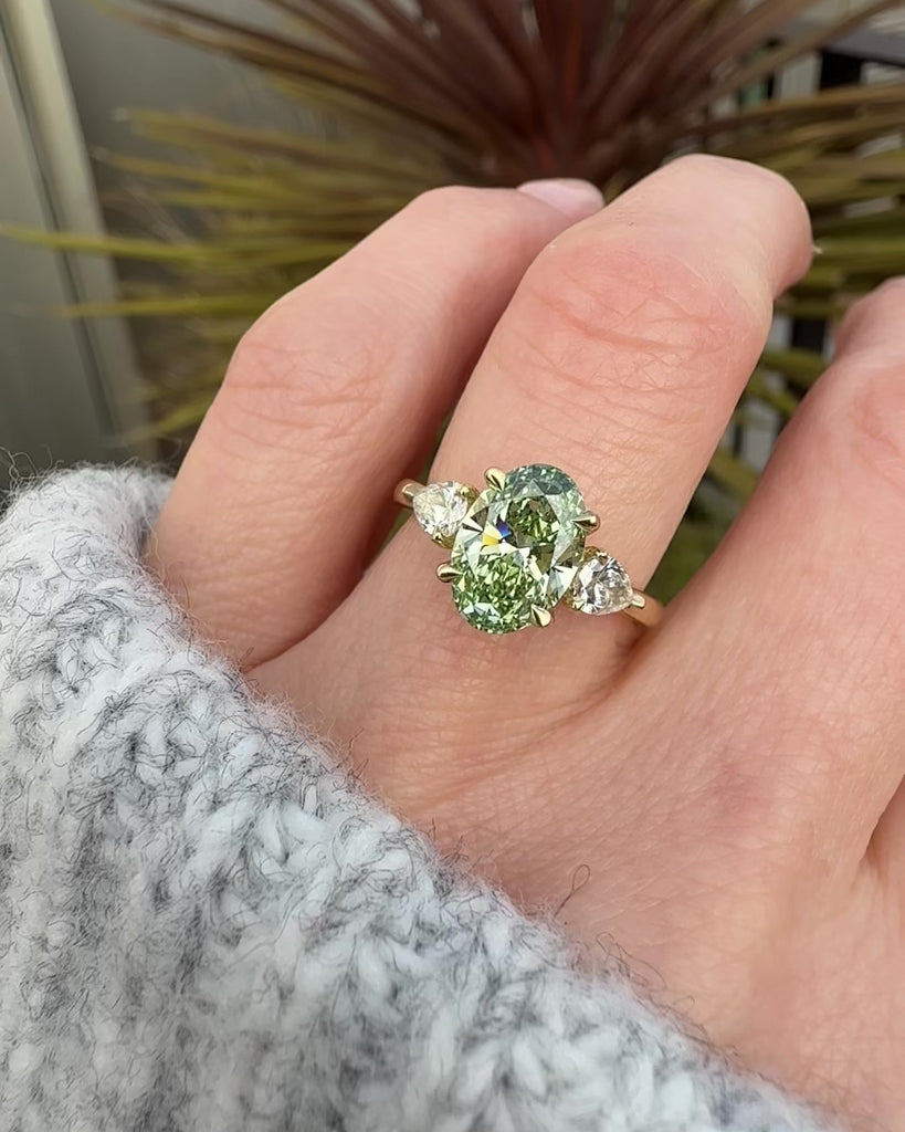 oval green lab grown diamond trilogy engagement ring in yellow gold