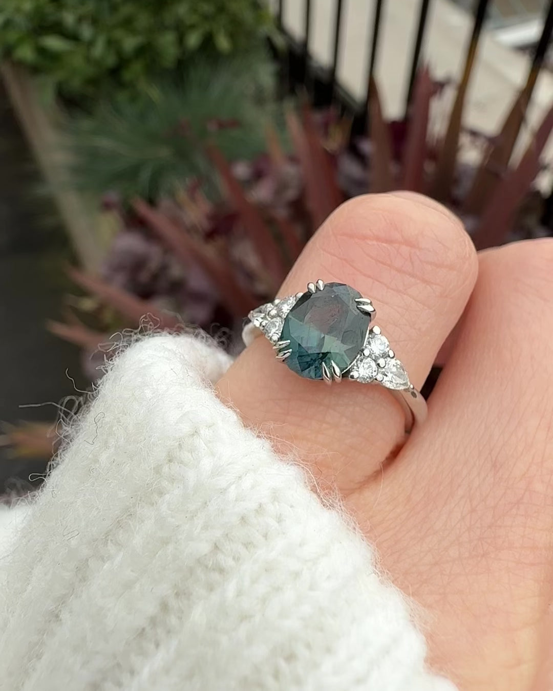 oval teal sapphire engagement ring set in platinum accented by six side diamonds