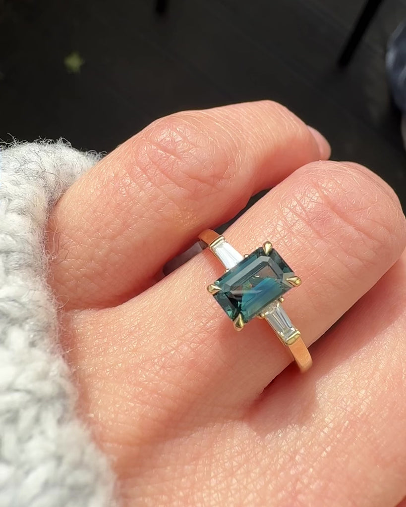 emerald cut teal sapphire trilogy engagement ring in yellow gold