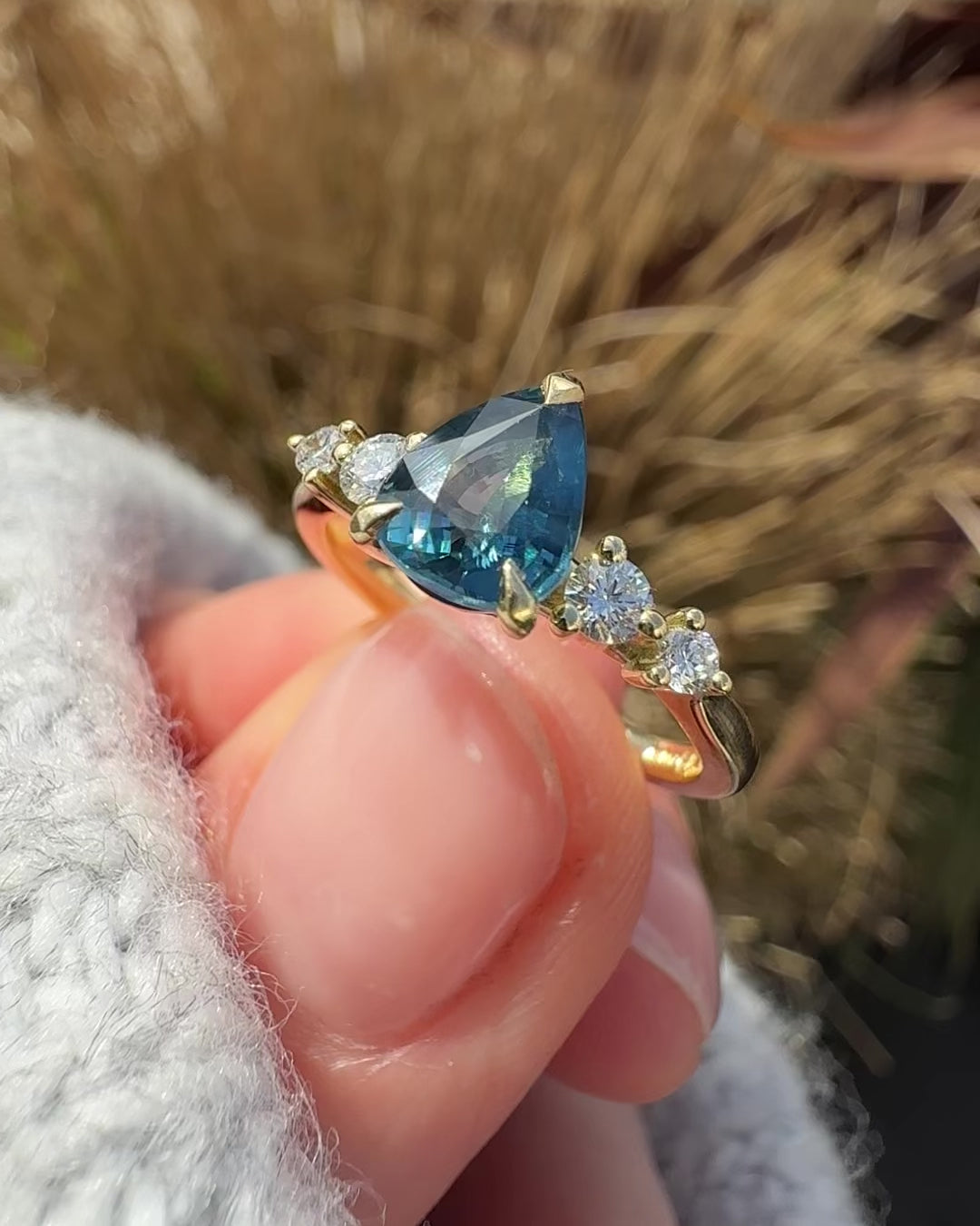 pear shape blue teal sapphire engagement ring set in yellow gold