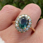 oval teal montana sapphire engagement ring in yellow gold with a diamond halo