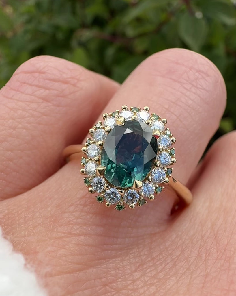 oval teal montana sapphire engagement ring in yellow gold with a diamond halo
