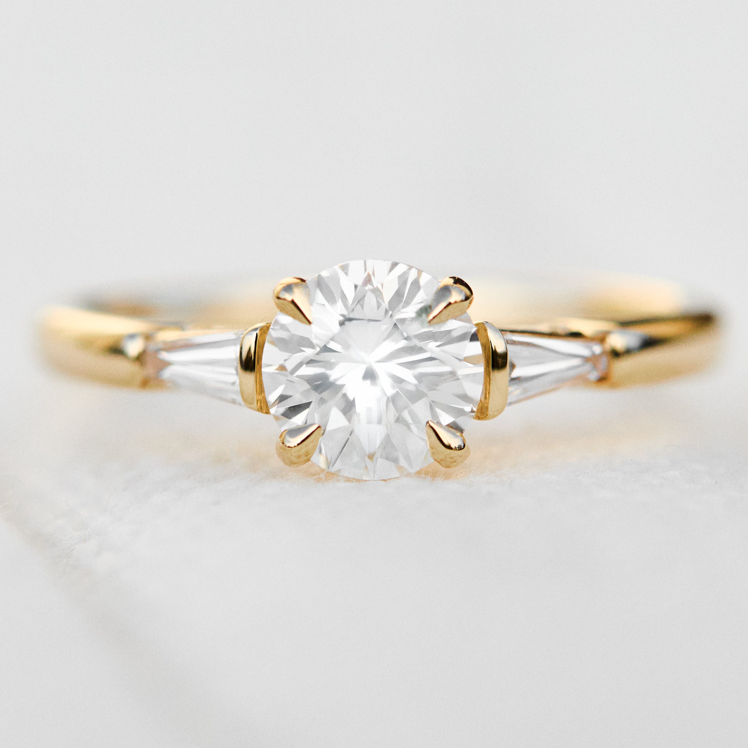 round brilliant cut diamond trilogy engagement ring with tapered baguette shoulders