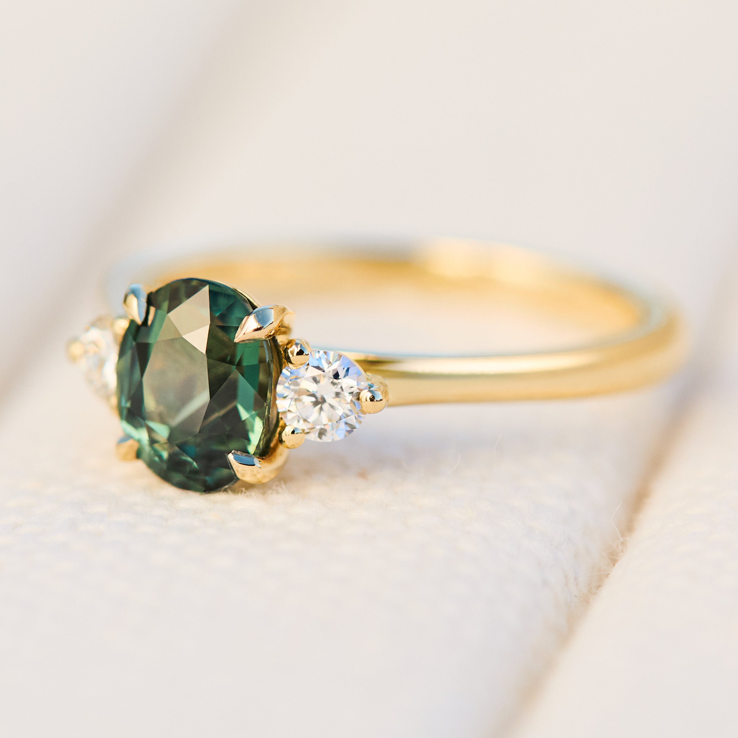 tanzanian oval teal sapphire trilogy engagement ring in yellow gold