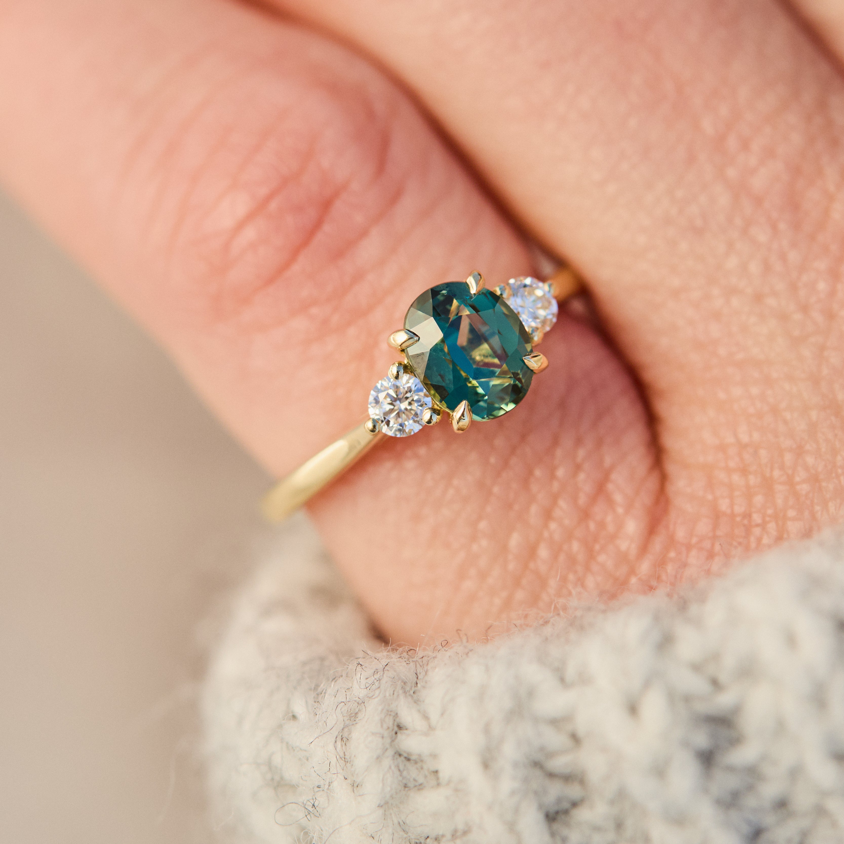 tanzanian oval teal sapphire trilogy engagement ring in yellow gold