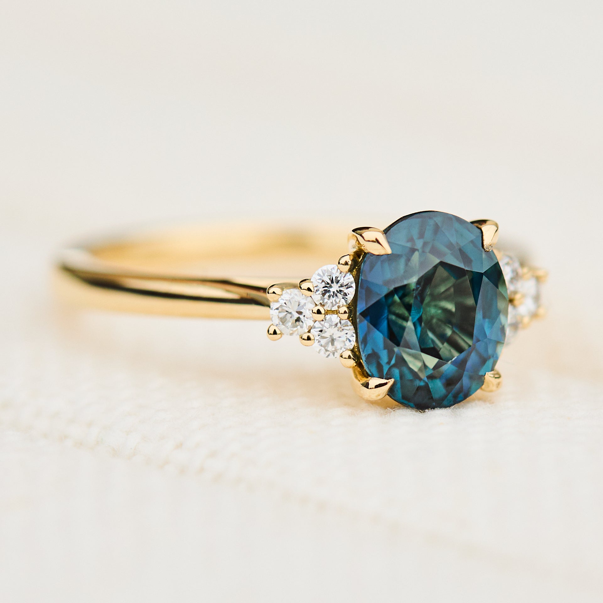 unheated teal blue oval sapphire engagement ring in yellow gold