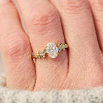 oval diamond engagement ring flanked by ten round side diamonds set in yellow gold